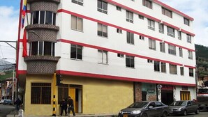 A multi-story building with a red and white facade, featuring balconies and a ground-level entrance. - Hotel Dancar (Pamplona)