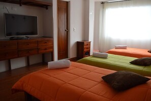 Ein Zimmer mit zwei Betten, einem Fernseher und einer Holzkommode.