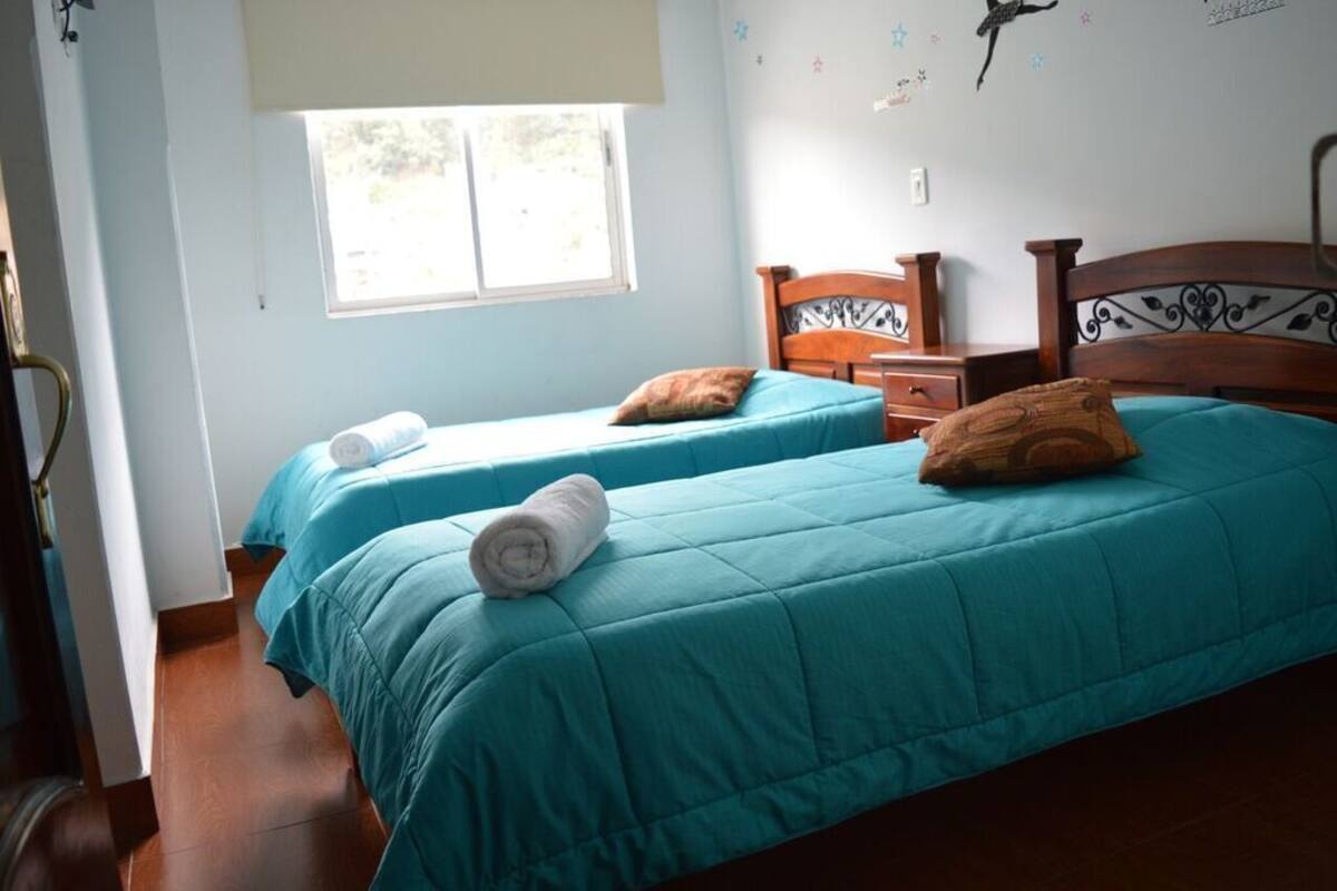 A room with two beds, a window, and a wooden nightstand.