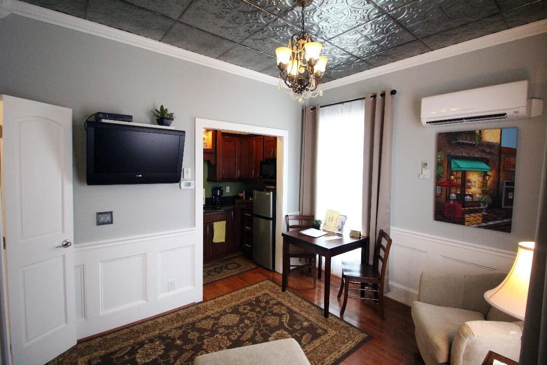 A living room with a television, a dining table, and a chandelier.