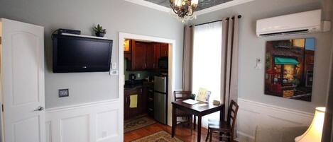 A living room with a television, a dining table, and a chandelier.