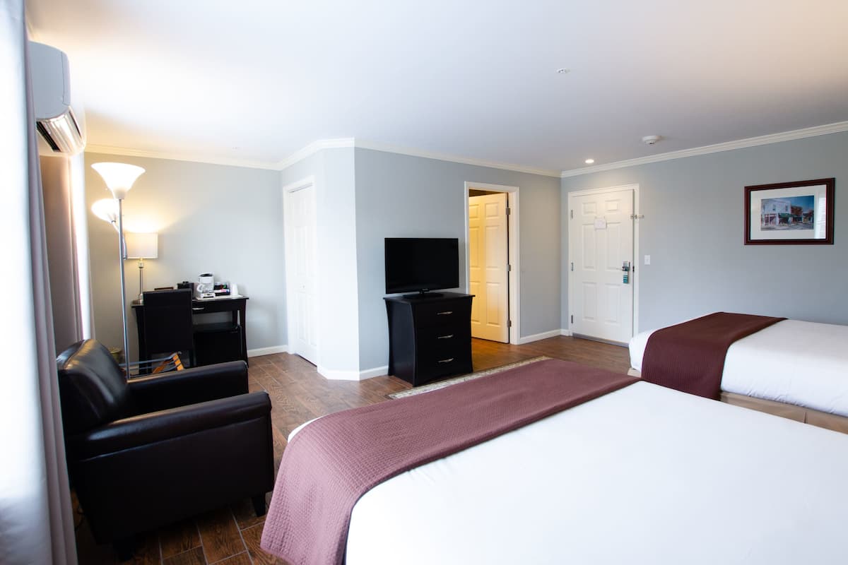 A hotel room with a bed, a desk, a chair, a television, and a door.