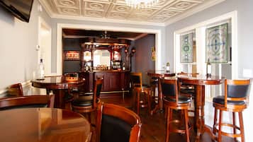 Uma área de bar com mobiliário de madeira, um balcão com garrafas e um candelabro.