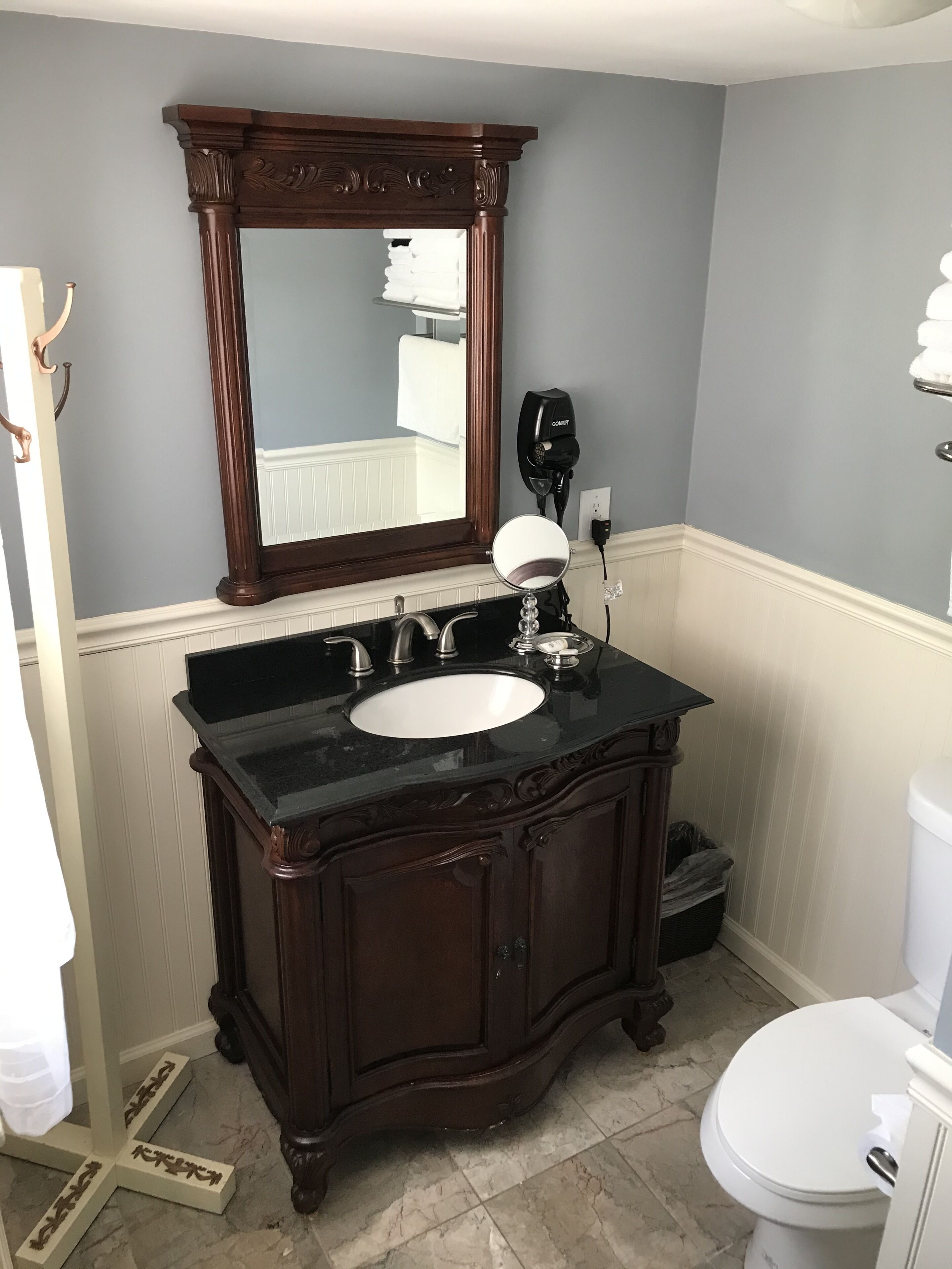 Un baño con tocador de madera oscura, un lavabo blanco y un espejo grande arriba.