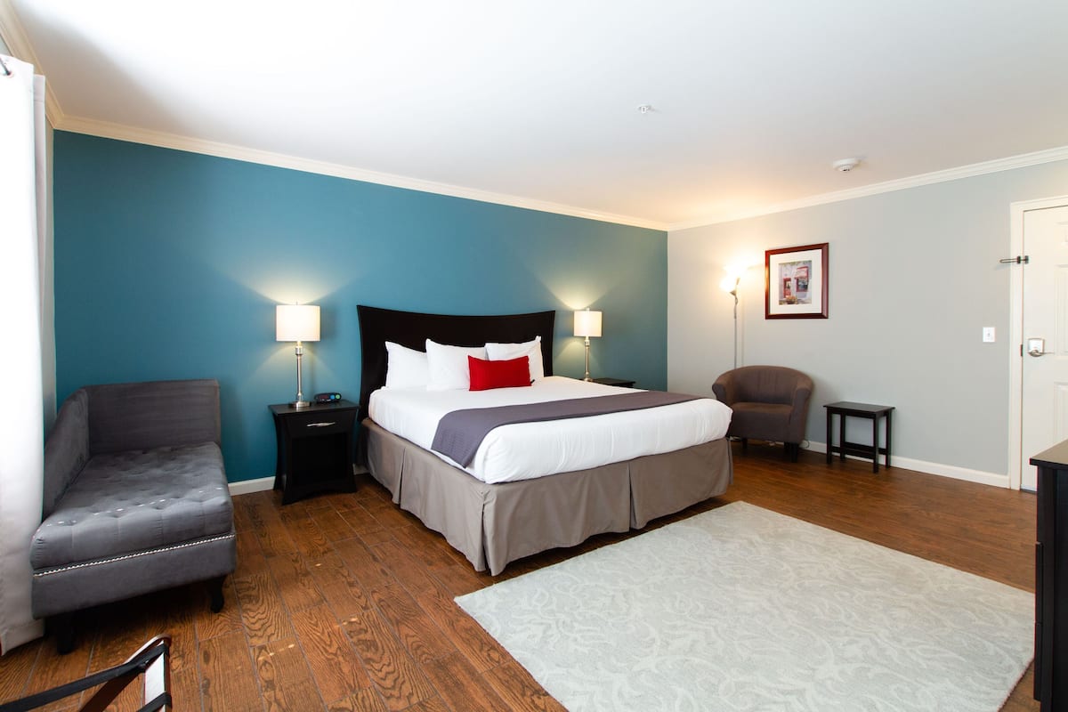 A bedroom with a bed, nightstands, a chair, a desk, and a door.
