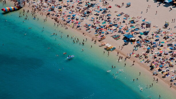An aerial view of a crowded beach with numerous umbrellas and people. - Apartments Biserka (Novalja)
