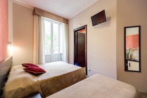 A hotel room with two beds, a window with curtains, a door, a mounted TV, and a framed picture on the wall. - Buonarroti Suite (Rome)