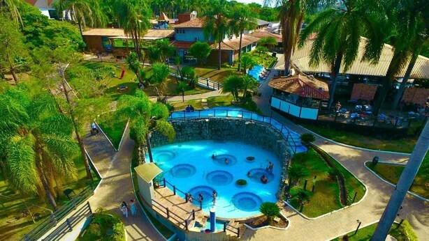 Un área de piscina con varias fuentes circulares, rodeada de senderos y palmeras.