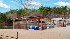 Zona ribereña con una playa de arena, estructuras de madera y un pabellón.
