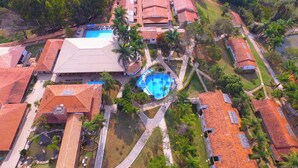 Un resort con varias edificaciones, una piscina central y follaje circundante.