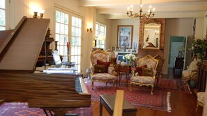 A grand piano, ornate chairs, a chandelier, and a large mirror in a spacious room with patterned rugs and wooden flooring. - The Colonels B&B and Inn (Athens)