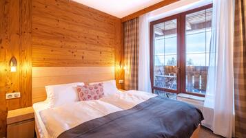A wooden-paneled bedroom with a large bed, a nightstand, and a window with curtains.