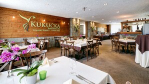 A restaurant interior with wooden walls, white ceiling, and tables set for dining.