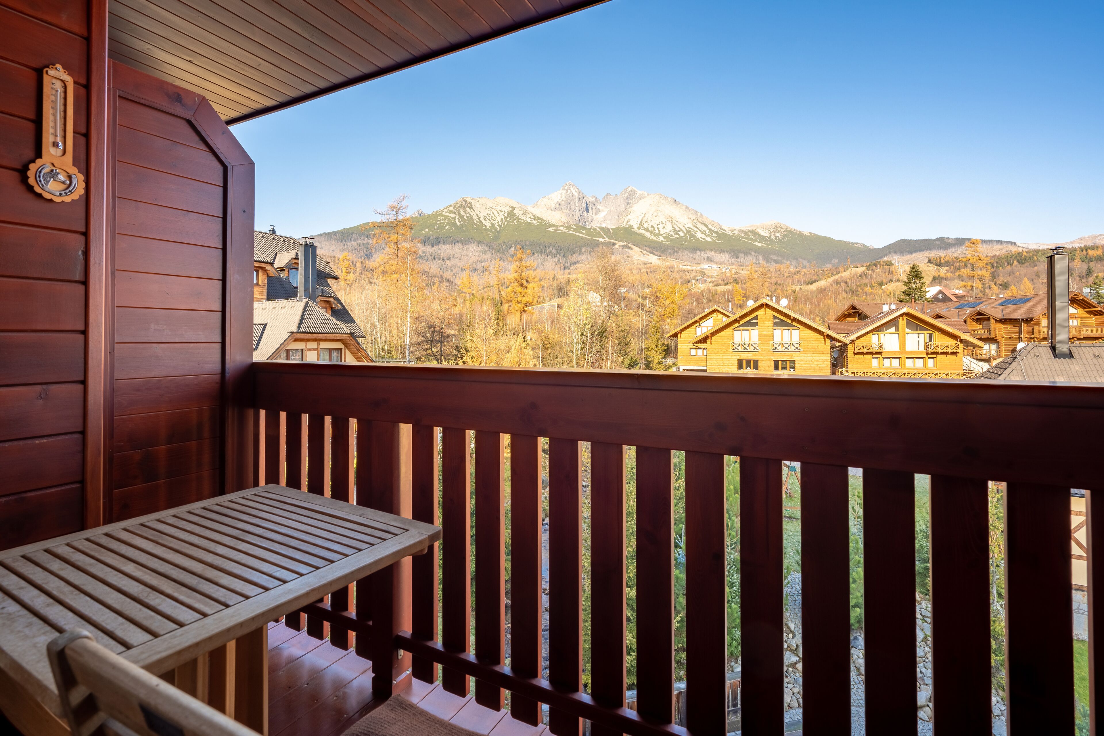 A wooden cabin with a balcony overlooking a mountain range.