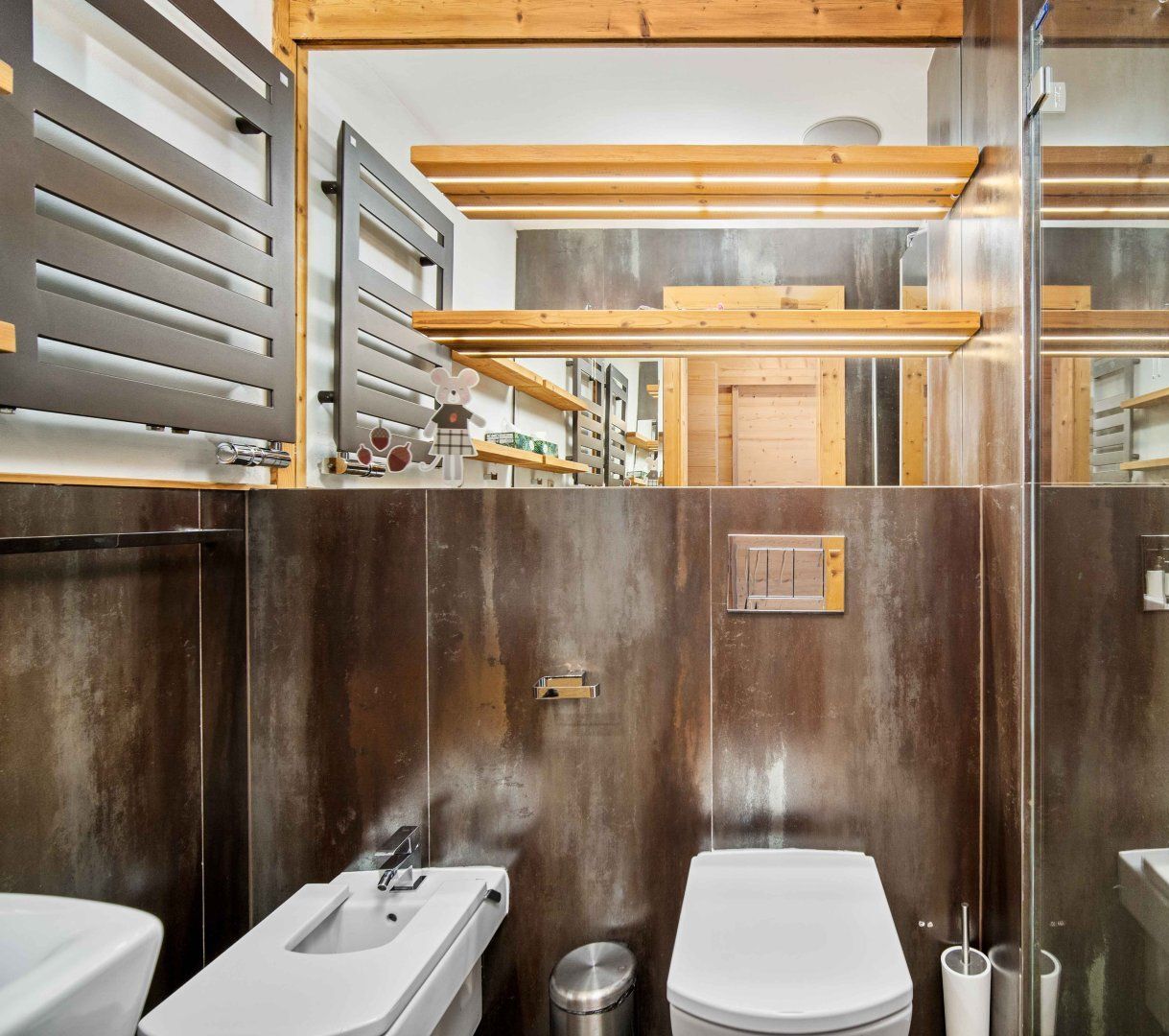Un baño moderno con techo de madera, un espejo grande y un lavabo de acero inoxidable.