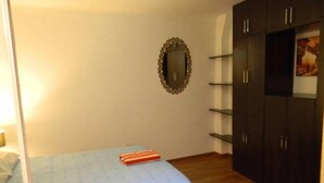 Un dormitorio con cama, espejo y armario.