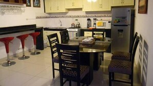 Una cocina compacta con comedor, que incluye un refrigerador, estufa y taburetes de bar.