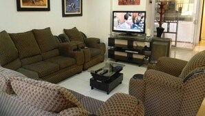 Una sala de estar con un conjunto de sofá, una mesa de centro, un televisor y cuadros en las paredes.