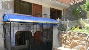 Un área vallada con toldo azul, un muro de piedra y una puerta de madera.