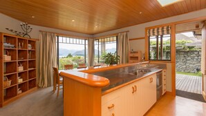 Uma cozinha com armários de madeira, uma ilha central e grandes janelas com vista para o exterior.