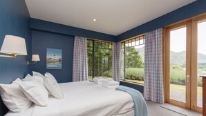 Quarto com uma cama grande, vista para o exterior e janela com cortinas.