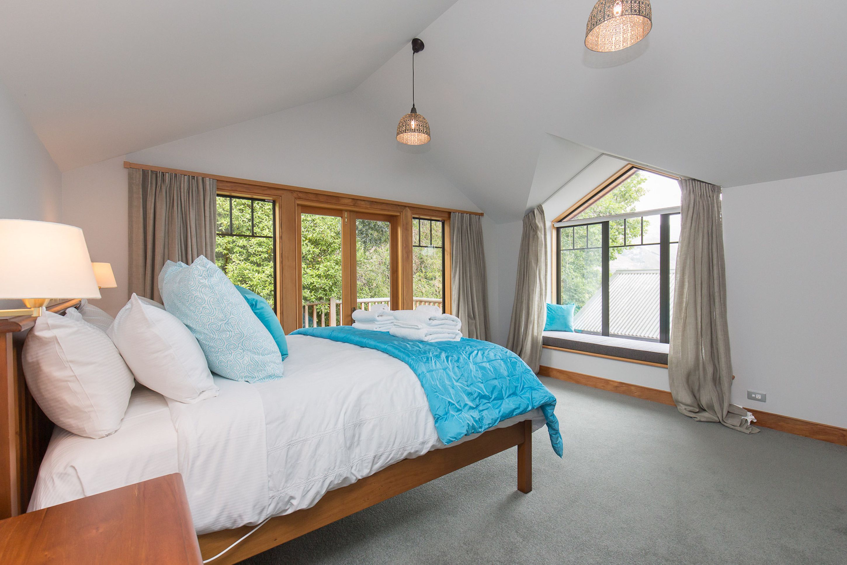 A bedroom with a large bed, a nightstand, a lamp, and a window with curtains.