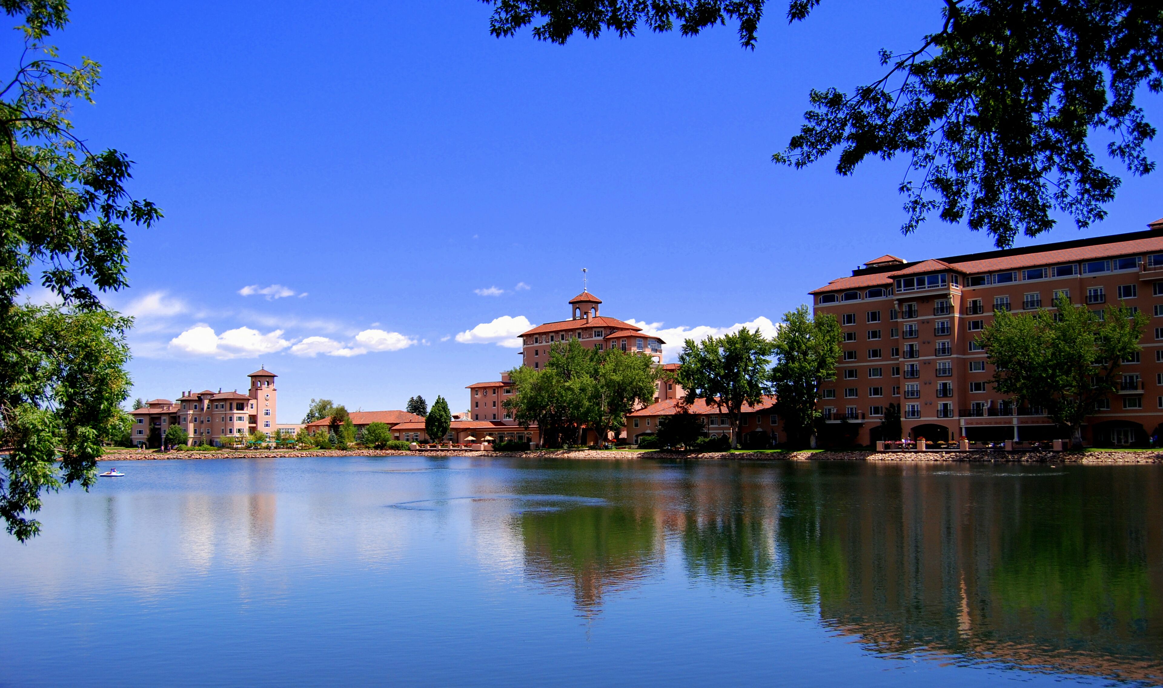 A large hotel with multiple buildings and a lake in the foreground.