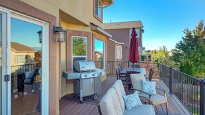 Une terrasse dotée de mobilier d’extérieur, d’un barbecue et d’une fenêtre donnant sur un quartier résidentiel.