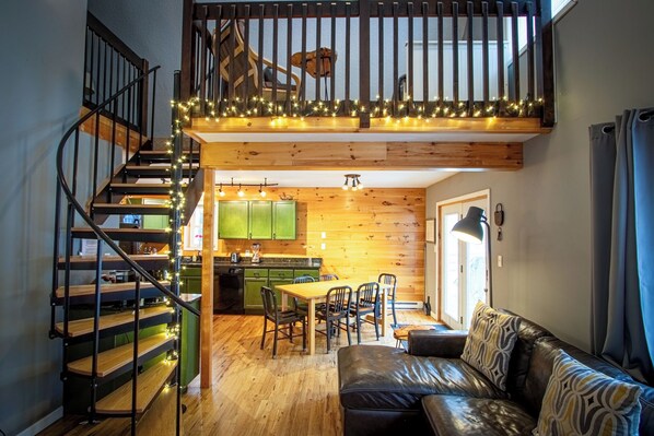 Un espacio habitable tipo loft con una escalera de madera, un comedor y una zona de estar acogedora.