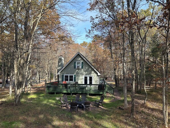 A cabin with a porch, surrounded by trees.