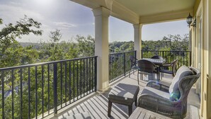 A balcony with a table and chairs, a small stool, and a view of a forested area. - Unit 405, 2BR on Rooftop Pool Floor, Steps to Coligny, SeaCrest Pool Access (Hilton Head Island)