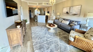 A modern living room with a grey sofa, a coffee table, and a dining area with a kitchen in the background. - Unit 405, 2BR on Rooftop Pool Floor, Steps to Coligny, SeaCrest Pool Access (Hilton Head Island)