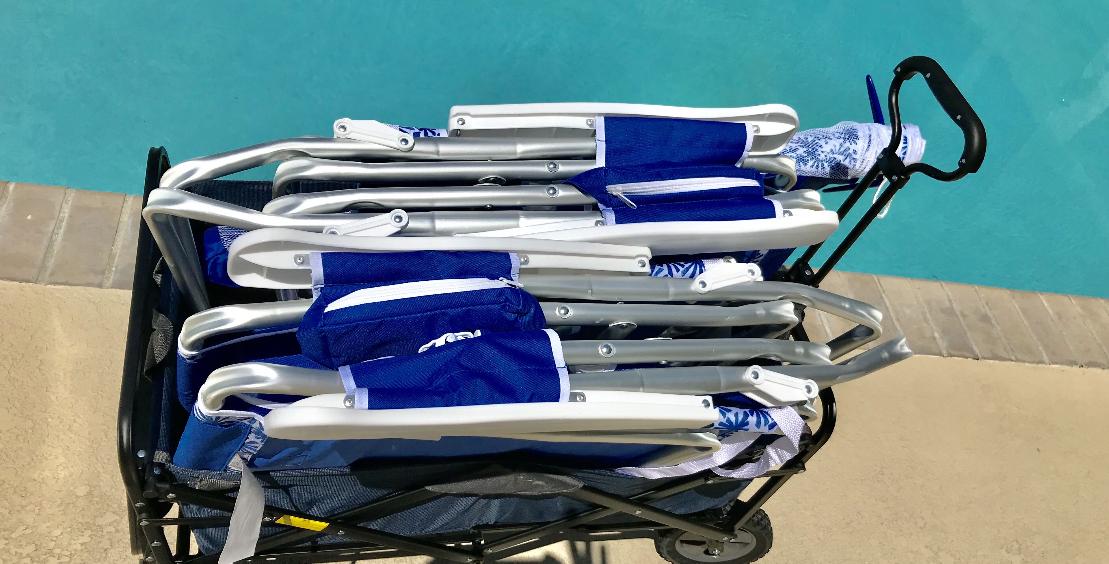 A poolside chair cart with multiple chairs, some with blue covers, and a water bottle on the side.