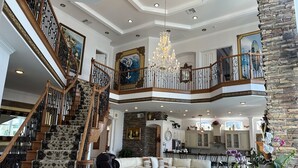 Ein geräumiger Wohnbereich mit hoher Decke, einer imposanten Treppe und einem Chandelier.