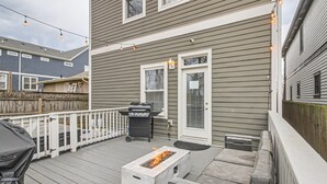 Eine Terrasse mit Feuerstelle, Grill und überdachter Sitzgruppe.