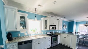 Une cuisine moderne avec des meubles blancs, un plan de travail en granit, un lave-vaisselle, une cuisinière et un four à micro-ondes.