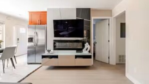 A modern kitchen with a built-in TV, stainless steel appliances, and a dining area with a table and chairs.