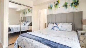 A bedroom with a large bed, a wardrobe, and a mirror.
