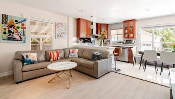 A modern living room with a sectional sofa, a round coffee table, and a dining area with white chairs.