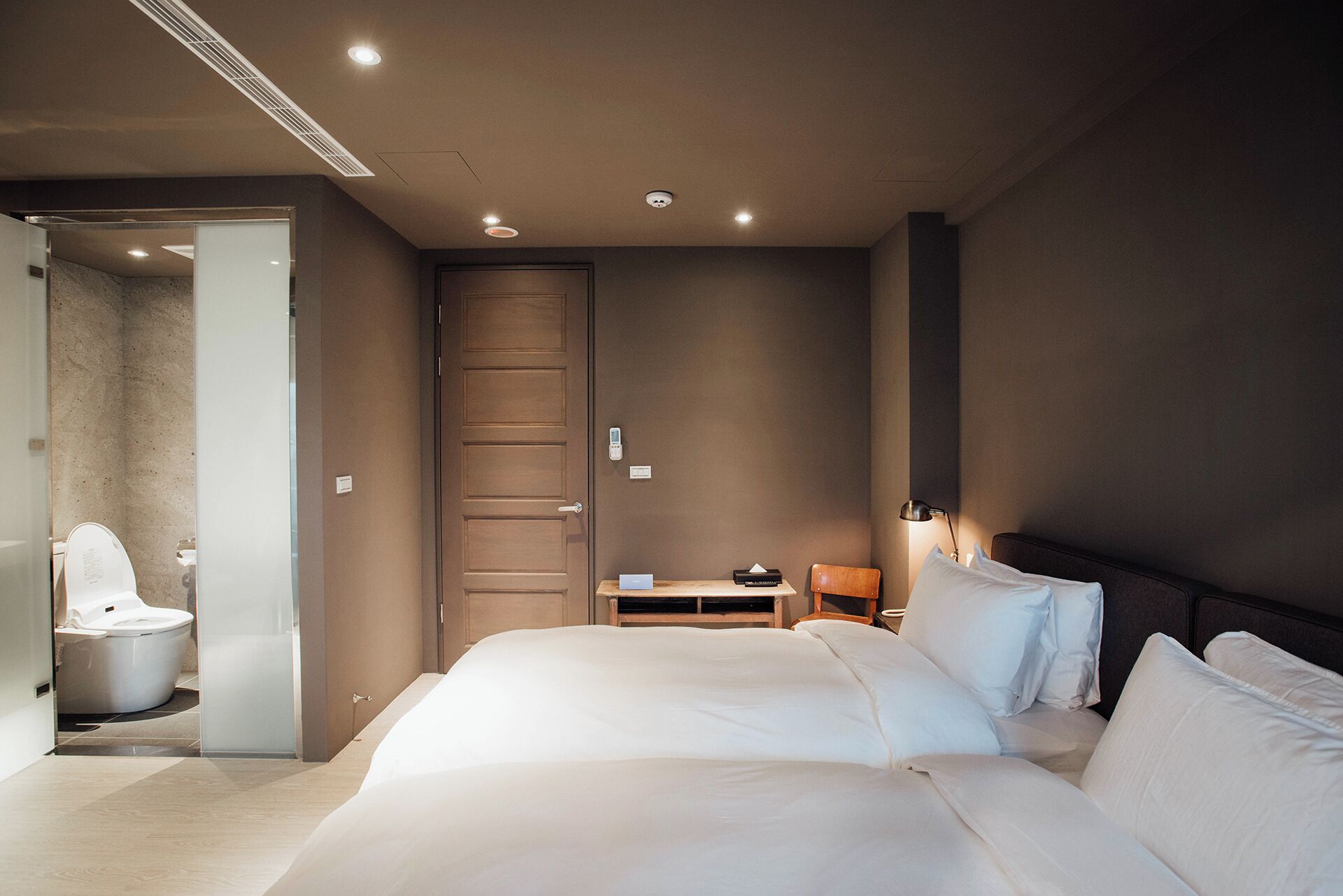 A modern hotel room with a large bed, a desk, and a chair.