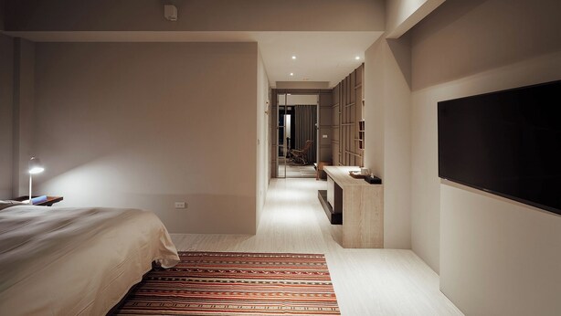 A modern hotel room with a bed, a desk, a TV, and a mirror.