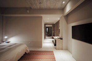 Une chambre d’hôtel moderne équipée d’un lit, d’un bureau, d’une télévision et d’un miroir.