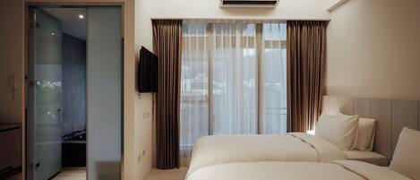 Una habitación de hotel con una cama, un televisor y un balcón al que se accede por una puerta corredera.