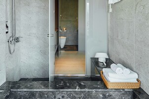 A modern bathroom with a shower, a toilet, and a sink. There is a wicker basket with towels on the counter.