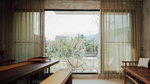 A dining area with a wooden table and benches, a white chair, and a small round table.