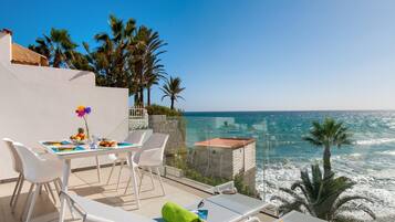 Een terras met een eettafel, loungestoelen en uitzicht op de oceaan.