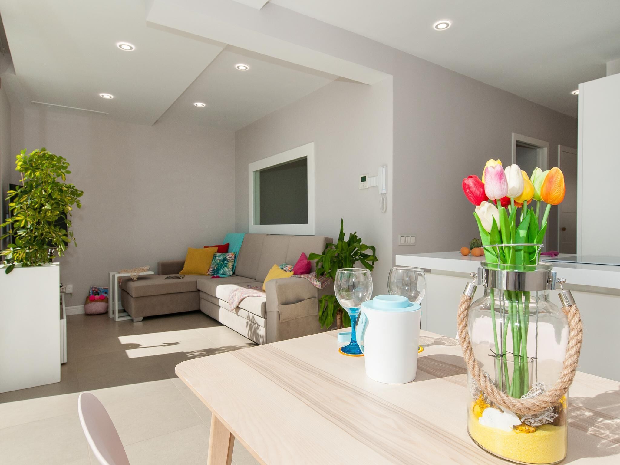 Een moderne woonkamer met een bank, een salontafel en een vaas met bloemen.
