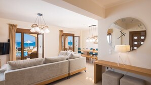 A modern living room with a sofa, dining area, and a large mirror. - Irida beachfront Villa for 12 next to all amenities (Rethymno)