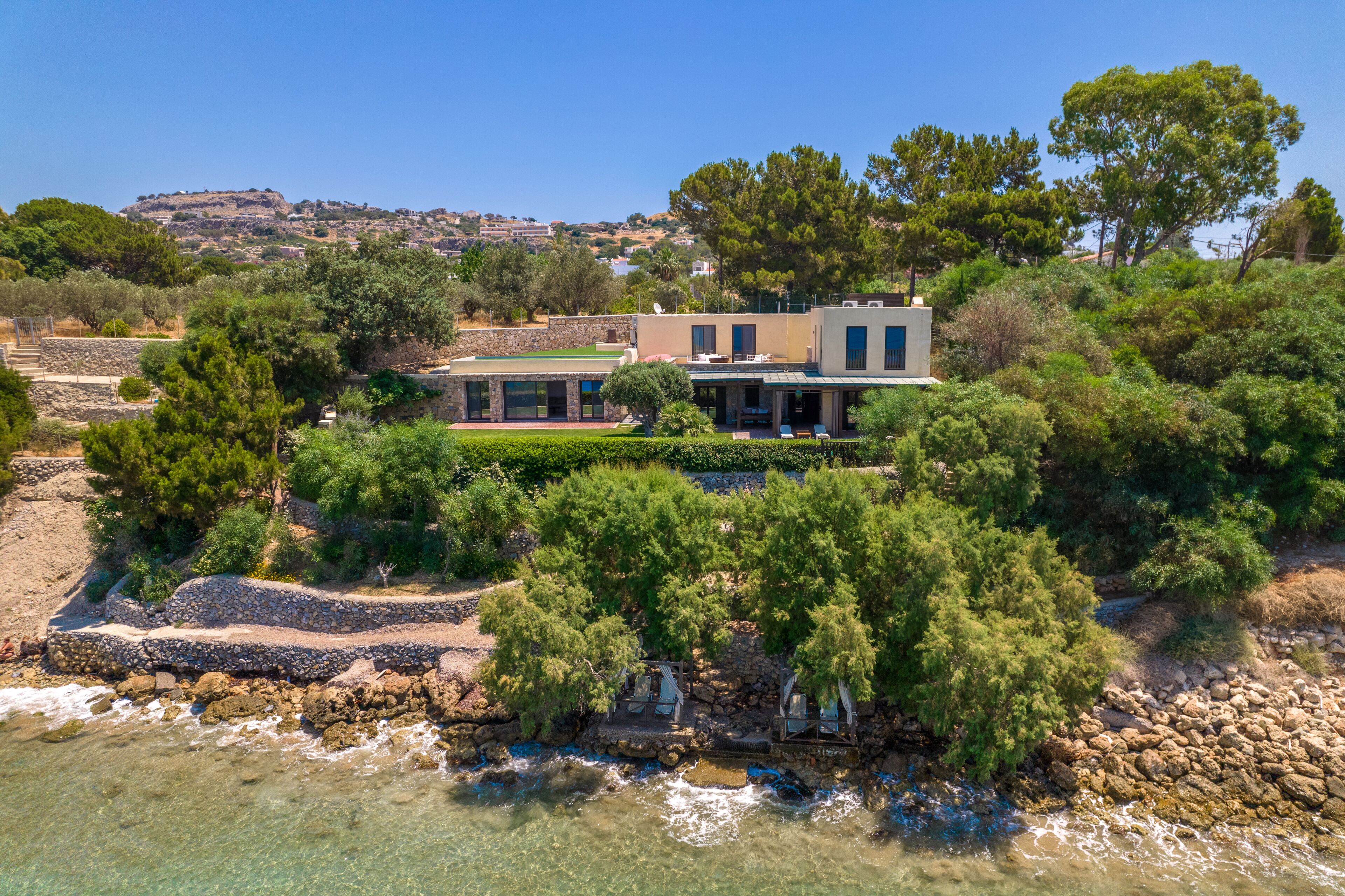 A coastal property with a large house, a private beach, and a rocky shoreline.