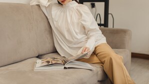 A person sitting on a sofa with a book. - Hostel Urby (Bangkok)